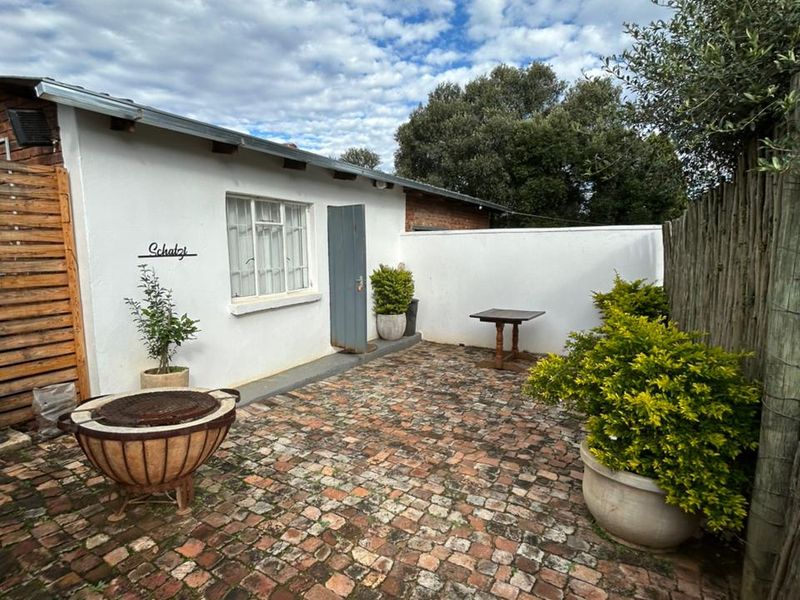 A private courtyard area featuring rustic brick paving, white rendered walls, and a wooden privacy fence, ideal for outdoor relaxation.