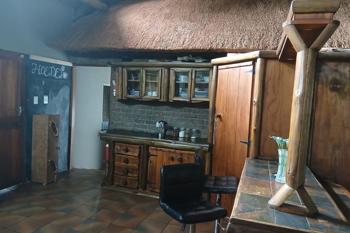 Rustic kitchen area featuring exposed brickwork, wooden cabinetry, and a traditional thatched roof ceiling, creating a warm, country-style atmosphere.