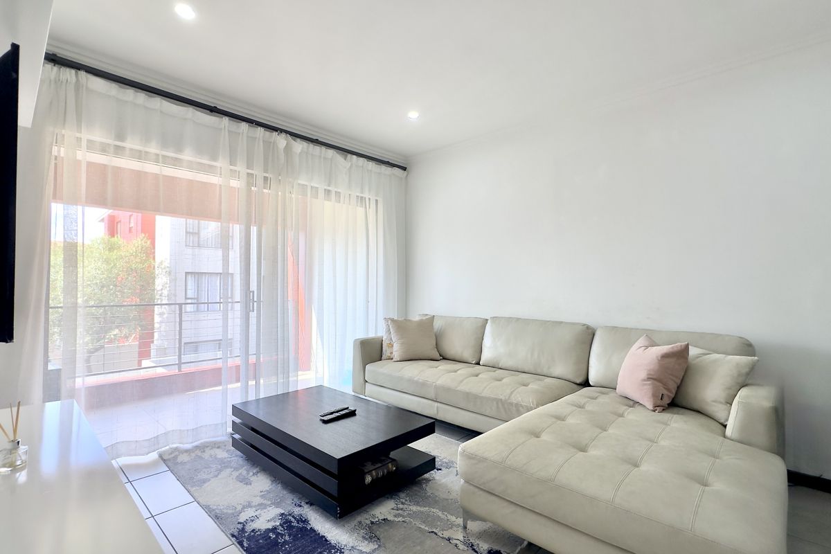 Bright and airy living room featuring large sliding glass doors that open onto a private balcony, providing ample natural light.