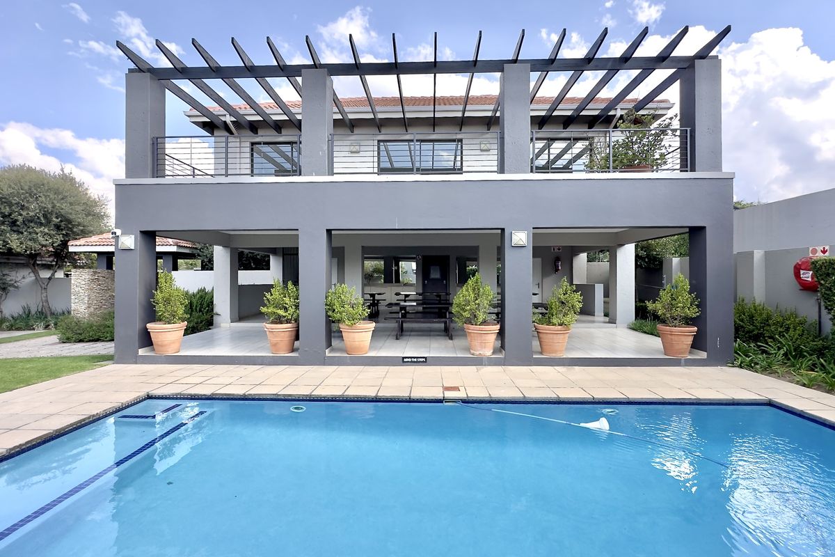 Rear view of the property featuring a swimming pool, a covered patio area, and an upper-level balcony with a pergola structure.