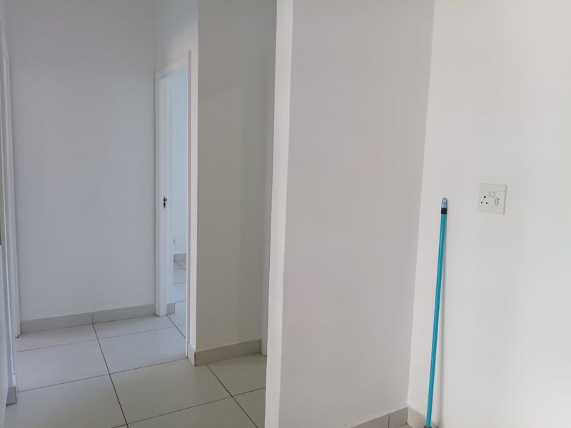 A clean, minimalist hallway featuring neutral tiled flooring and white walls, providing a bright and open transition between rooms in the apartment.