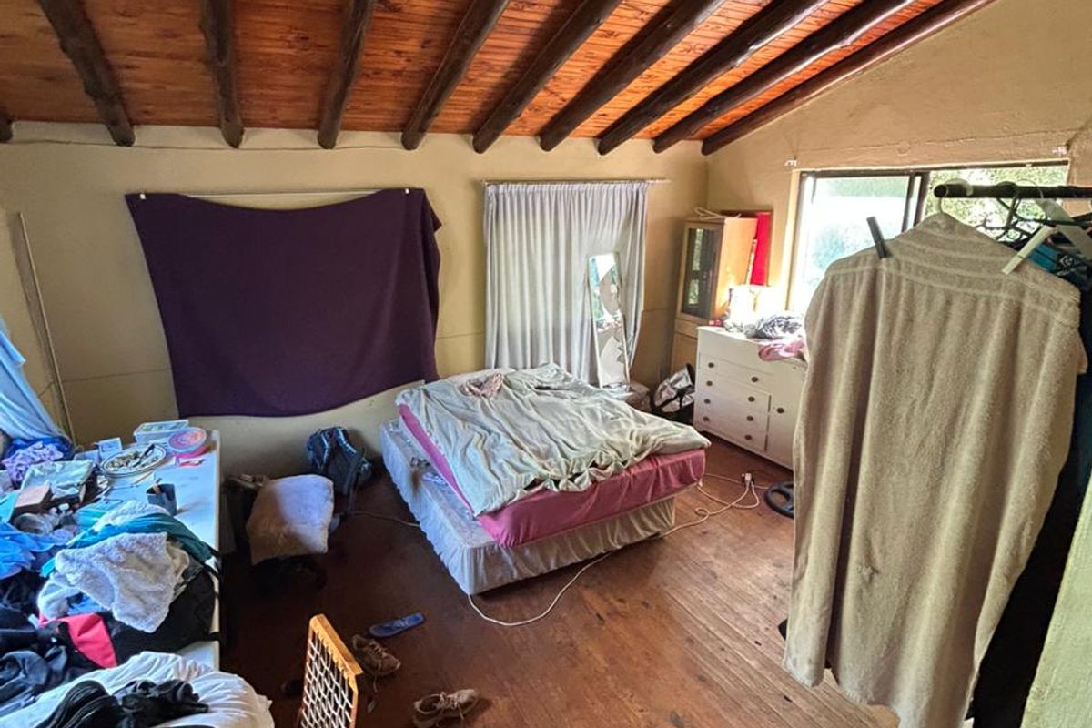 A bedroom featuring exposed timber beam ceilings and wooden flooring, offering a rustic aesthetic with potential for modernization.