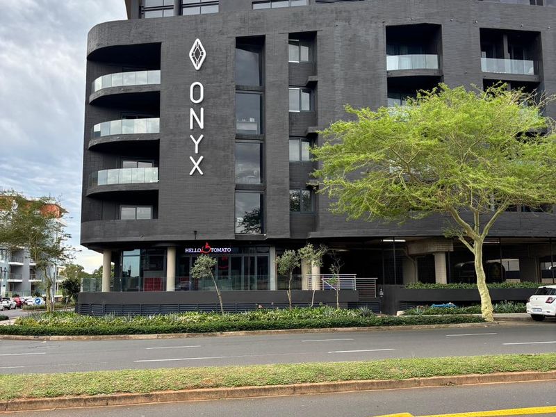 Exterior view of The Onyx apartment building, featuring a modern dark facade, glass balconies, and ground-floor commercial space.