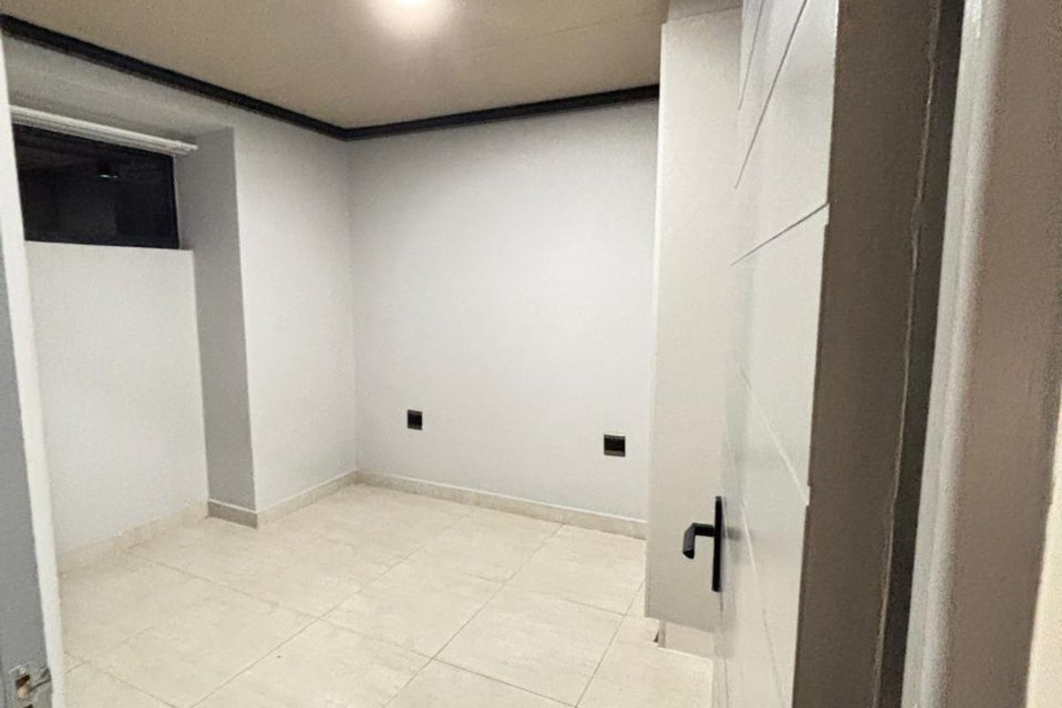 A vacant bedroom featuring neutral tiled flooring, recessed lighting, and a clean, minimalist aesthetic ready for personalization.