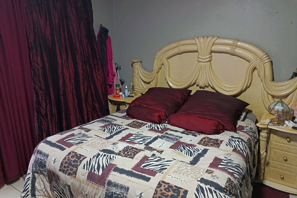 A bedroom featuring a built-in headboard and matching bedside tables, with tiled flooring and dark curtains.