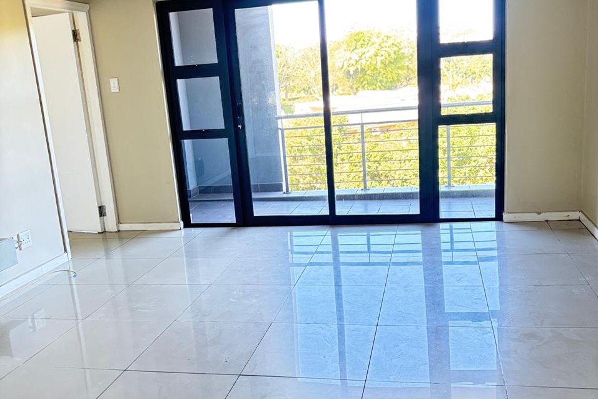 Bright and spacious living area featuring large sliding glass doors that open onto a private balcony, complemented by polished ceramic floor tiles.