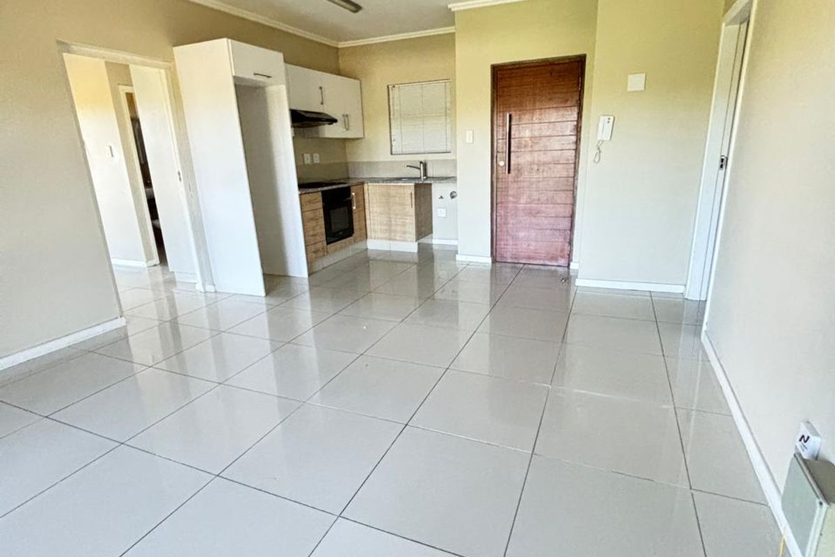Open plan living area featuring tiled flooring and a compact kitchen with built-in cabinetry, oven, and extractor fan.
