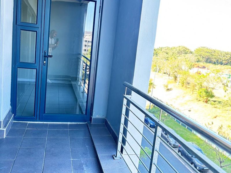 A private balcony featuring tiled flooring, a modern metal railing, and a glass-panelled door providing access to the interior.