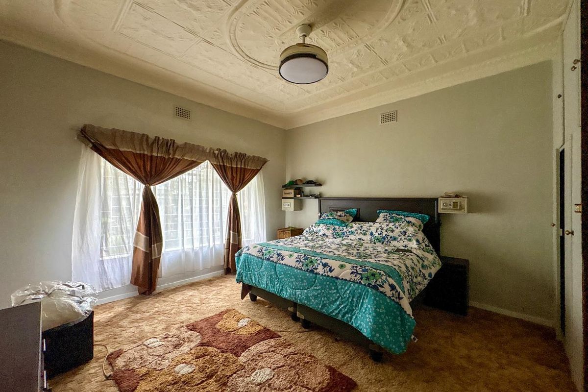 Spacious bedroom featuring a decorative pressed metal ceiling, large window with natural light, and neutral wall tones.
