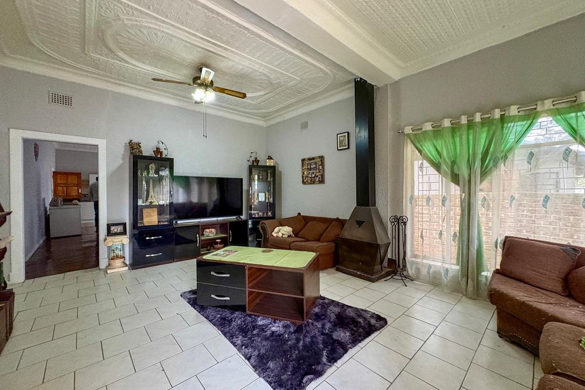 Spacious living room featuring a decorative pressed ceiling, tiled flooring, and a built-in metal fireplace, offering a comfortable and traditional living space.