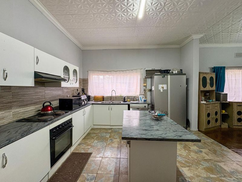 A functional kitchen featuring white cabinetry, stone-look countertops, a central island, and a built-in oven with an extractor fan.
