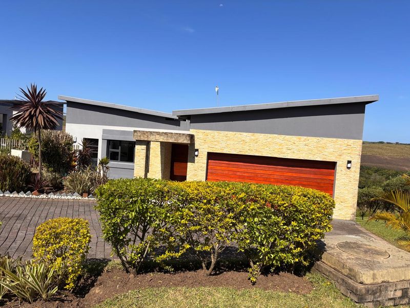 Modern single-story residence featuring a striking skillion roof, stone-clad facade, and a double garage, set within a well-maintained landscaped garden.