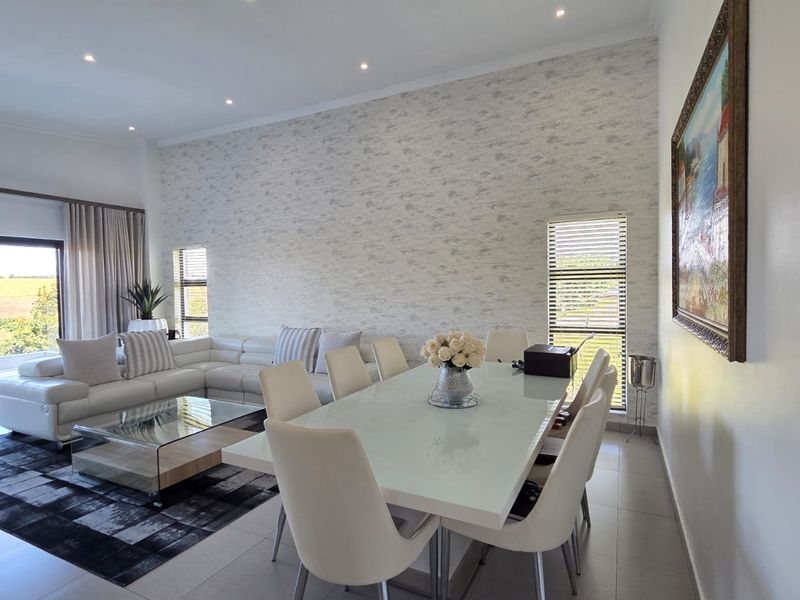 Spacious open-plan living and dining area featuring tiled floors, recessed lighting, split-system air conditioning, and a feature wallpaper wall with large windows.