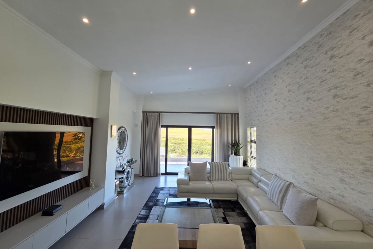 Spacious modern living room featuring a textured feature wall, built-in media cabinetry with timber detailing, recessed lighting, and large sliding doors leading to the outdoors.