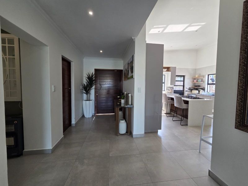Spacious open-plan entrance hall leading into a modern kitchen with a central island, tiled flooring, and contemporary finishes throughout.