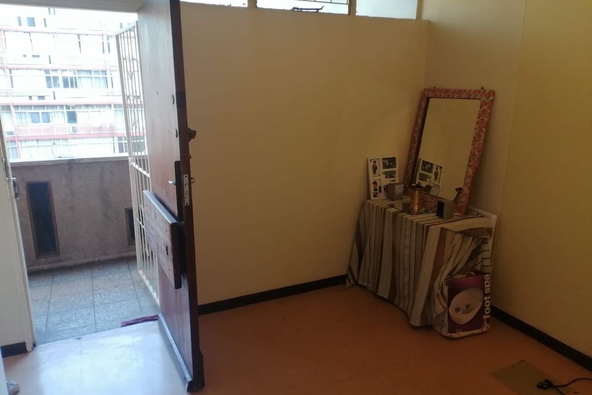 An entry area featuring a solid wood door leading to an exterior balcony, with basic flooring and neutral wall finishes.