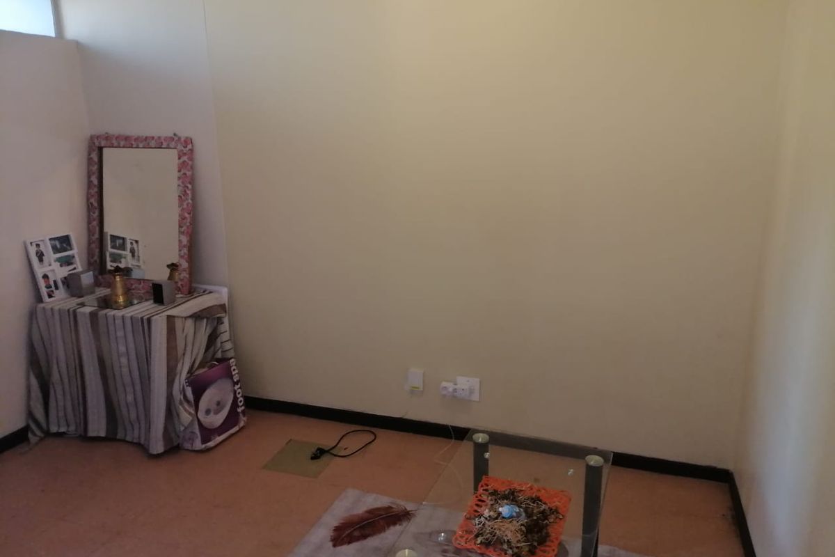 A sparsely furnished room featuring plain walls, electrical outlets, and basic flooring, suitable for use as a bedroom or home office.