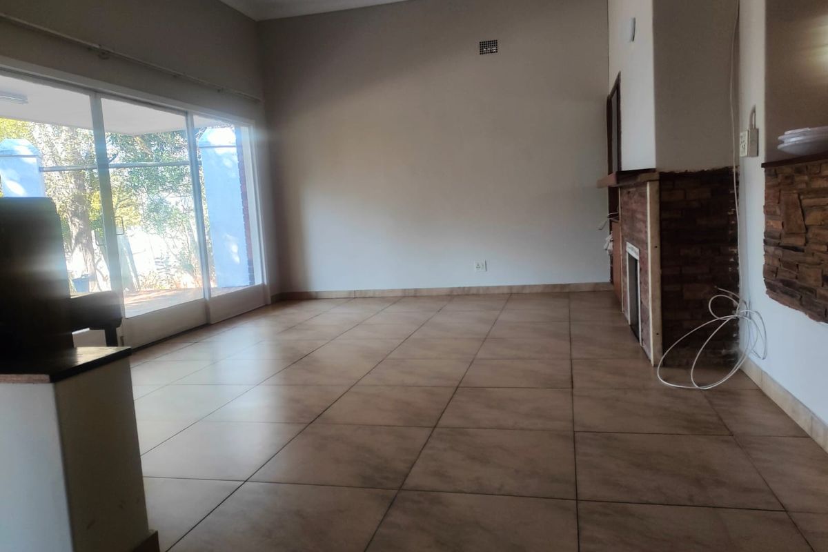 Spacious living area featuring large sliding glass doors, tiled flooring, and a brick-accented fireplace, offering a bright and open layout.