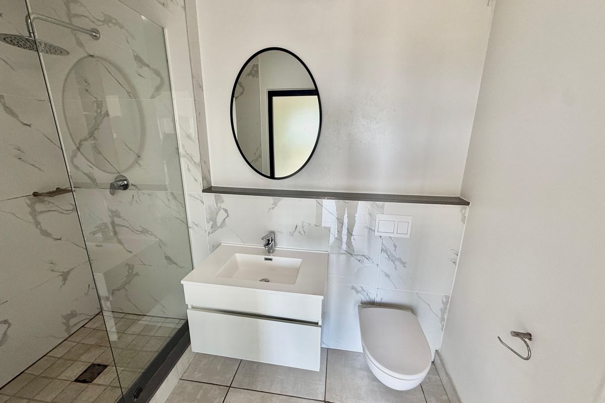 Modern bathroom featuring a walk-in shower with marble-look tiling, a wall-mounted vanity with basin, and a concealed cistern toilet.