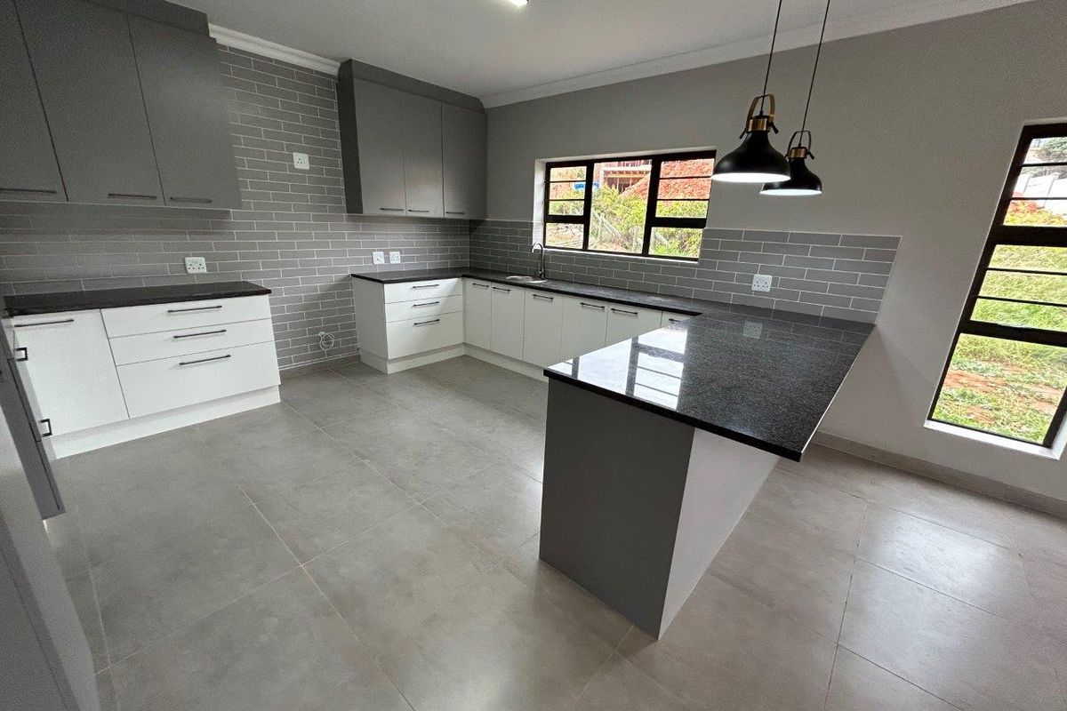 Modern kitchen featuring sleek two-tone cabinetry, granite countertops, subway tile backsplash, and large windows providing ample natural light.