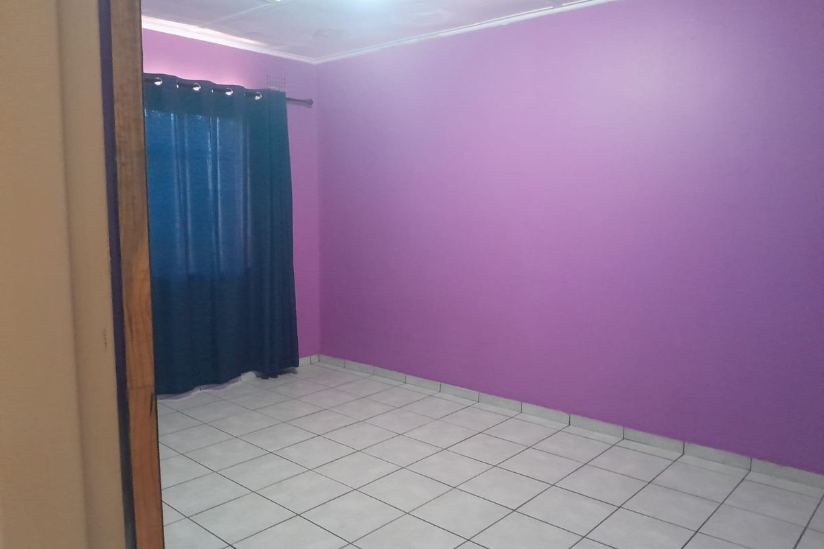 A vacant bedroom featuring tiled flooring and purple painted walls, viewed from the doorway.