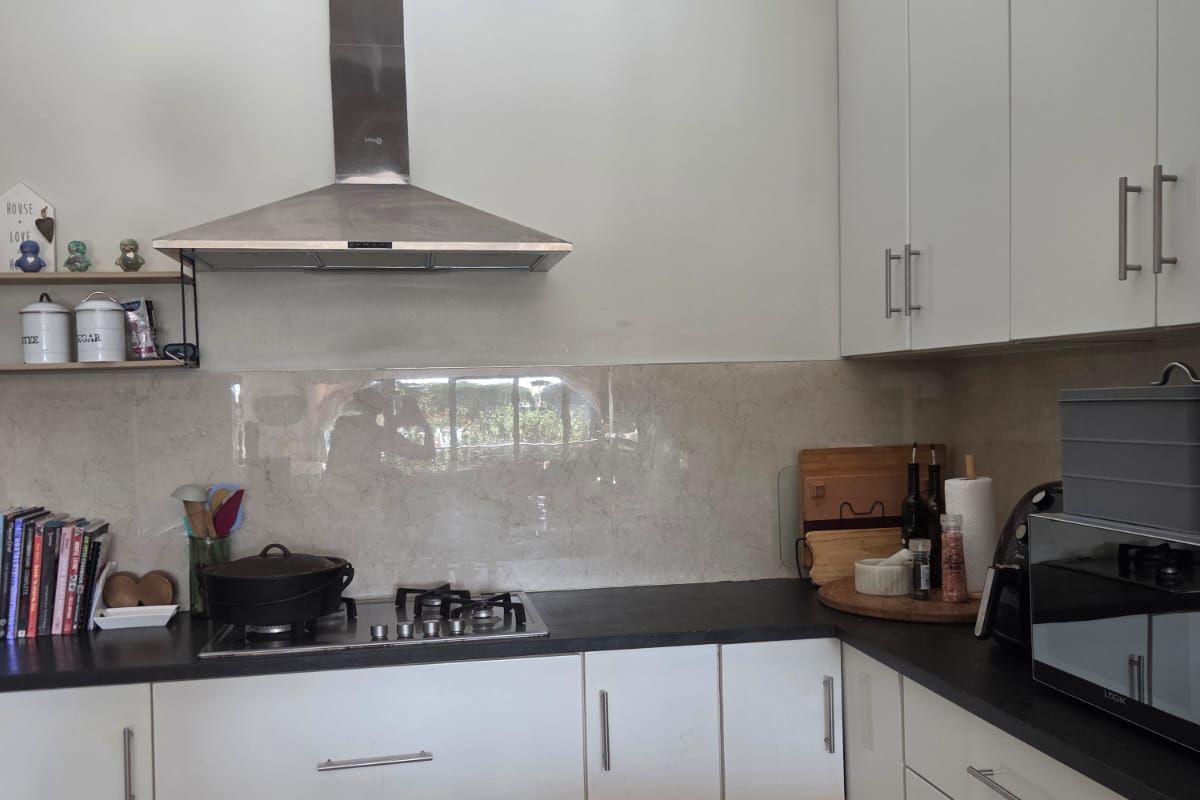 Modern kitchen featuring white cabinetry, dark countertops, a gas hob with stainless steel extractor fan, and neutral tiled flooring.