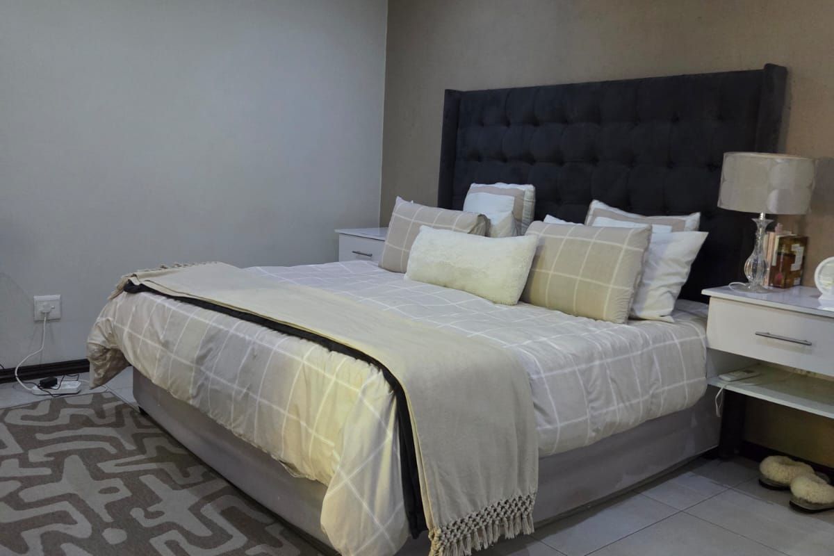 A well-maintained bedroom featuring tiled flooring, recessed downlighting, and a wall-mounted split-system air conditioning unit.
