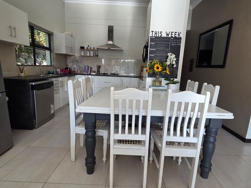 An open-plan kitchen and dining area featuring modern cabinetry, tiled flooring, and a functional layout with integrated cooking appliances.