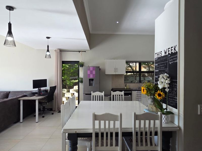 An open-plan living and dining area featuring tiled floors, recessed lighting, and a functional kitchen space with built-in cabinetry.