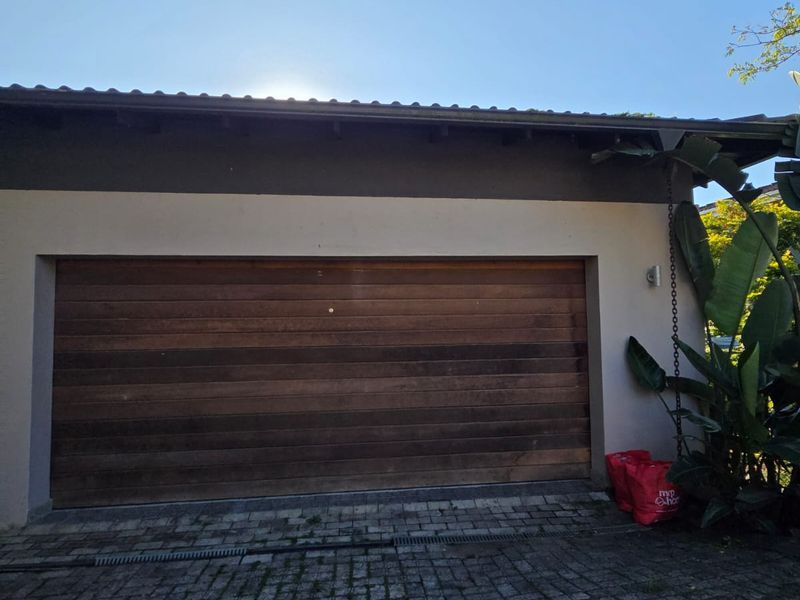Exterior view of a single garage featuring a timber sectional door and a paved driveway.