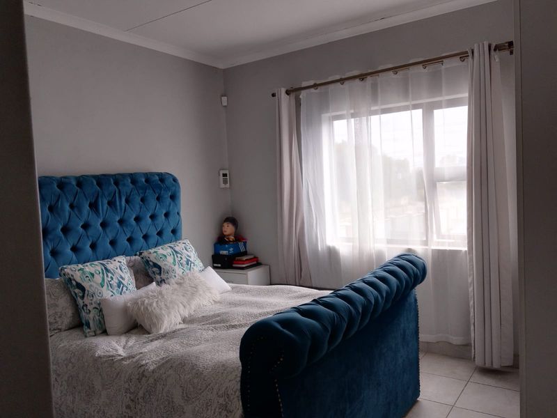 A well-maintained bedroom featuring neutral wall tones, tiled flooring, and a large window allowing for natural light.