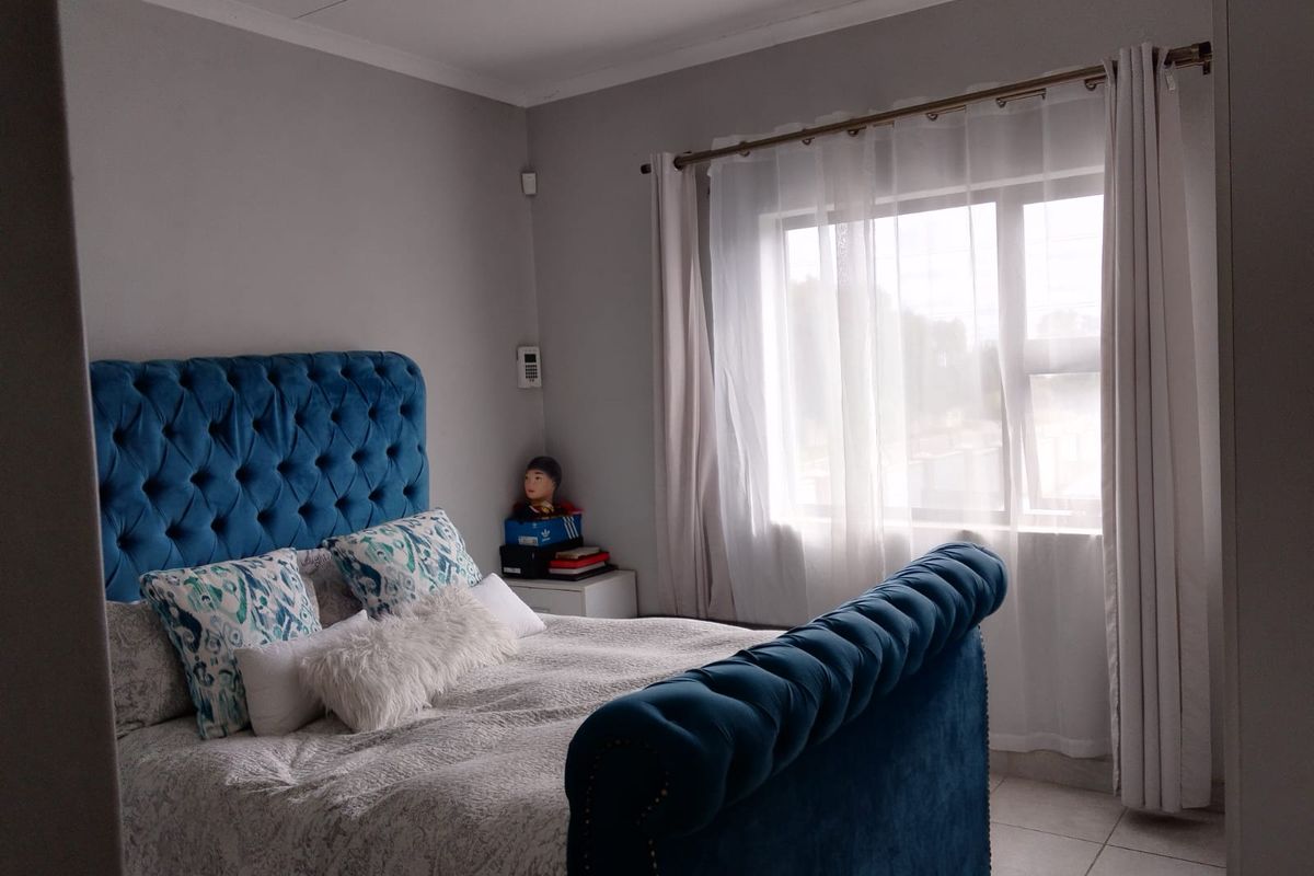 A well-maintained bedroom featuring neutral wall tones, tiled flooring, and a large window allowing for natural light.
