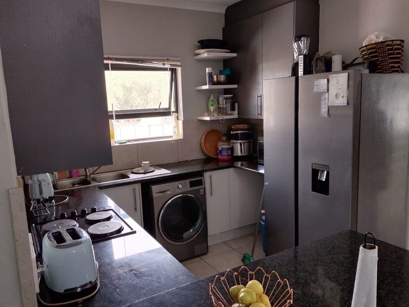 Compact kitchen featuring dark granite countertops, built-in cabinetry, a stainless steel sink, and an integrated washing machine.