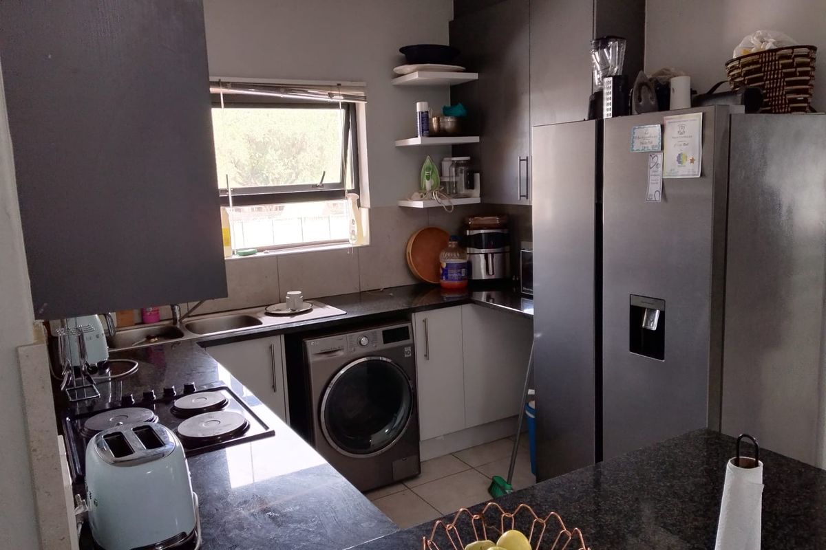 Compact kitchen featuring dark granite countertops, built-in cabinetry, a stainless steel sink, and an integrated washing machine.
