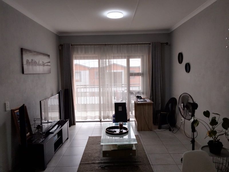 A living room featuring tiled flooring and a large sliding glass door that provides access to an outdoor balcony area.