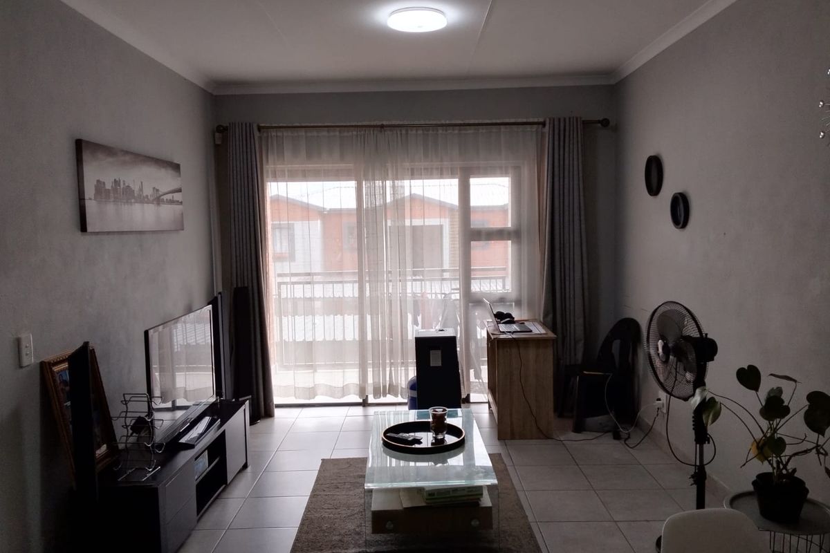 A living room featuring tiled flooring and a large sliding glass door that provides access to an outdoor balcony area.