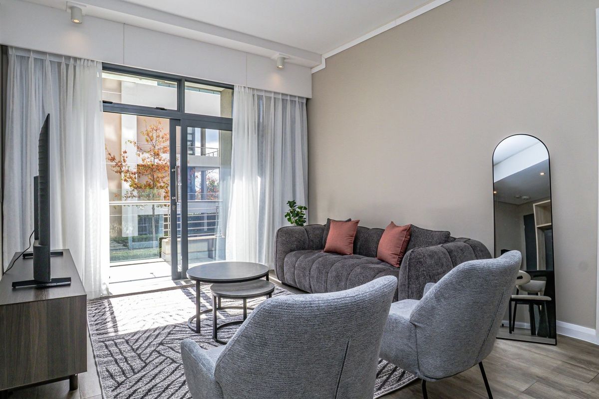 A bright and modern living room featuring large glass sliding doors that open onto a private balcony, providing ample natural light.