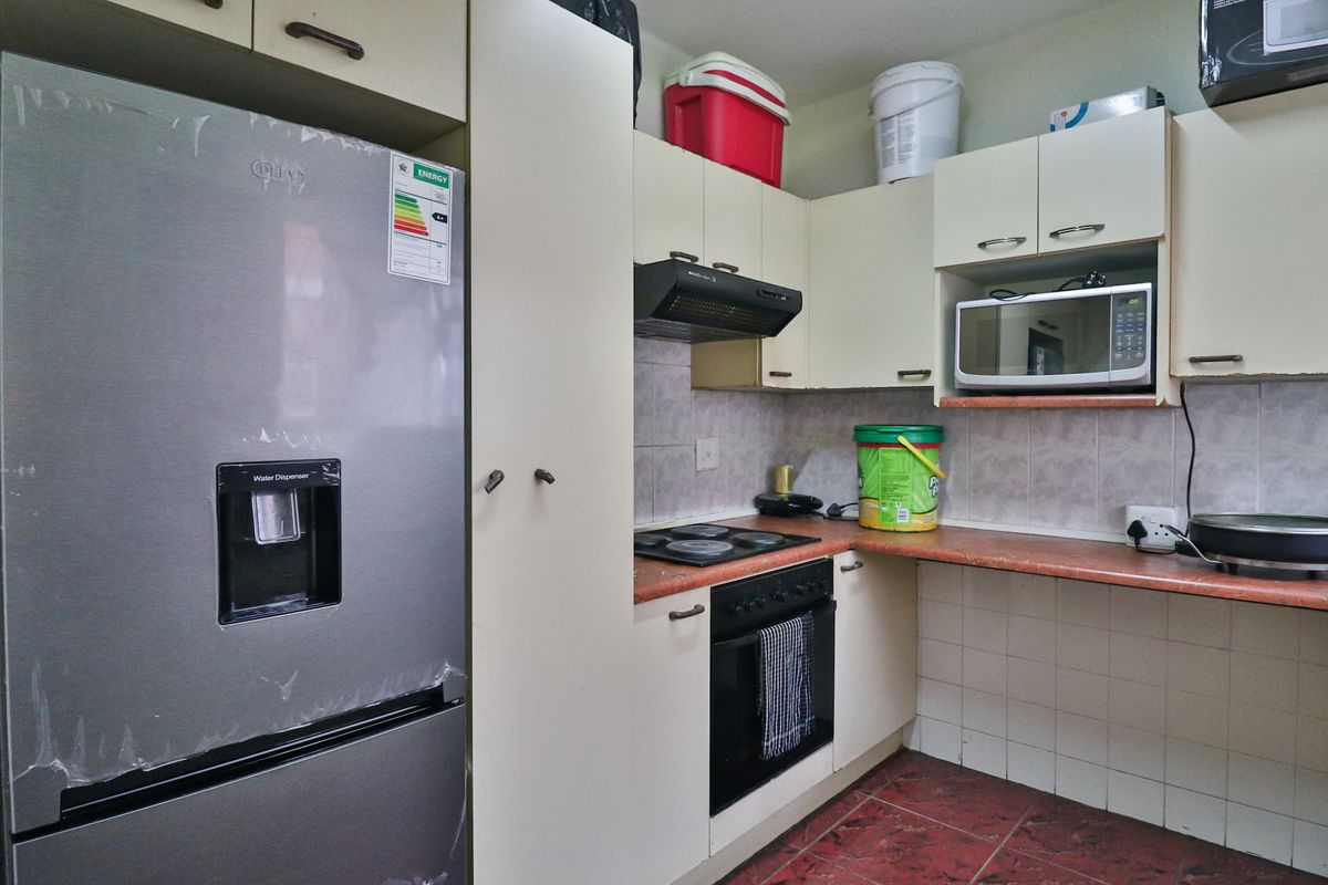 Compact kitchen featuring built-in cabinetry, integrated oven, electric hob, extractor fan, and tiled splashbacks with a functional layout.