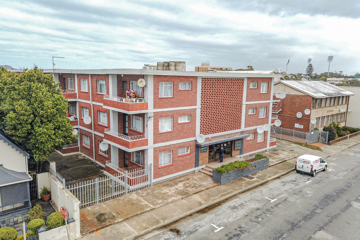 Aerial view of a multi-story brick apartment building featuring private balconies and a street-level entrance.
