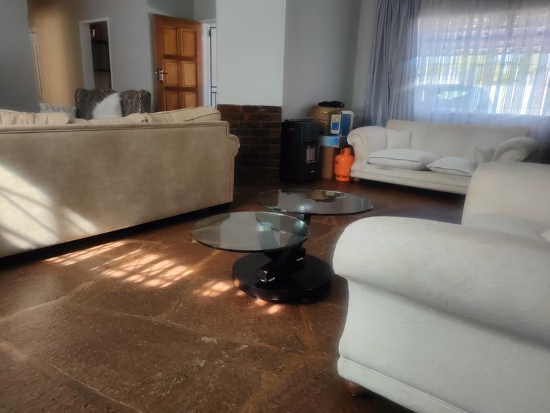 A spacious living room featuring natural stone flooring and a brick fireplace surround, offering a warm and traditional aesthetic.