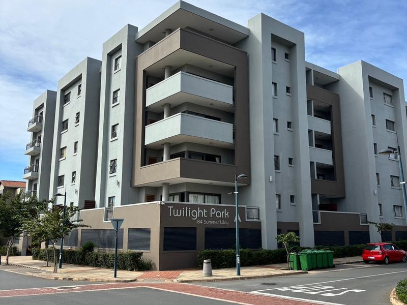 Exterior view of Twilight Park apartment complex, featuring modern multi-story architecture with balconies and secure perimeter fencing.