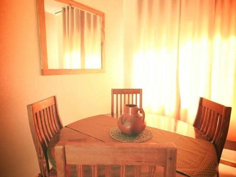 A dining area featuring tiled flooring and large window curtains, providing a functional space for meals.