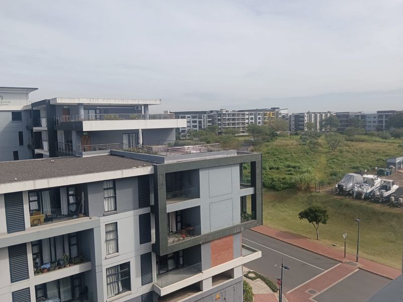 An elevated view overlooking a modern apartment complex with contemporary architectural design, balconies, and surrounding landscaped grounds.