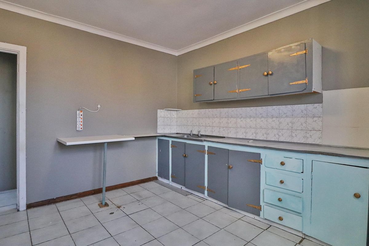 A dated kitchen featuring original cabinetry, a tiled backsplash, and tiled flooring, offering a blank canvas for renovation and modernization.