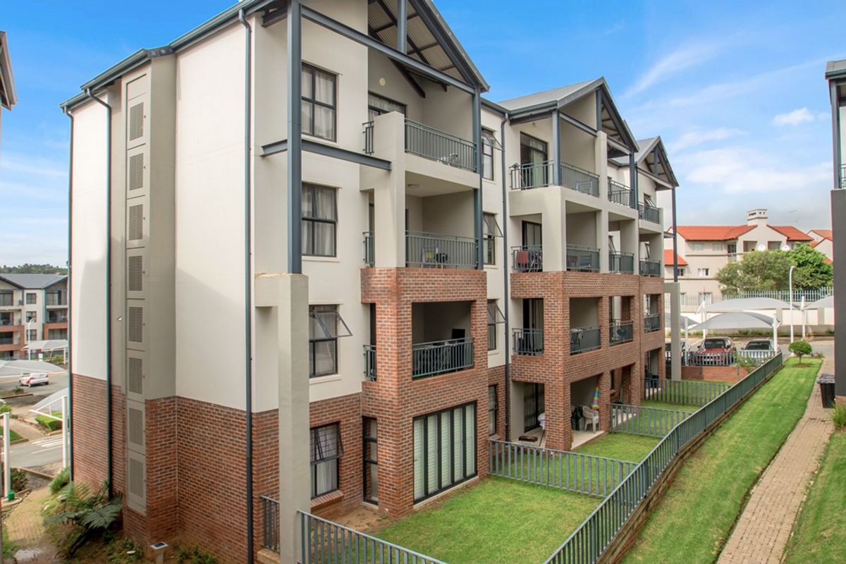 A multi-story apartment building featuring a mix of brick and rendered facade, private balconies, and ground-floor garden access.