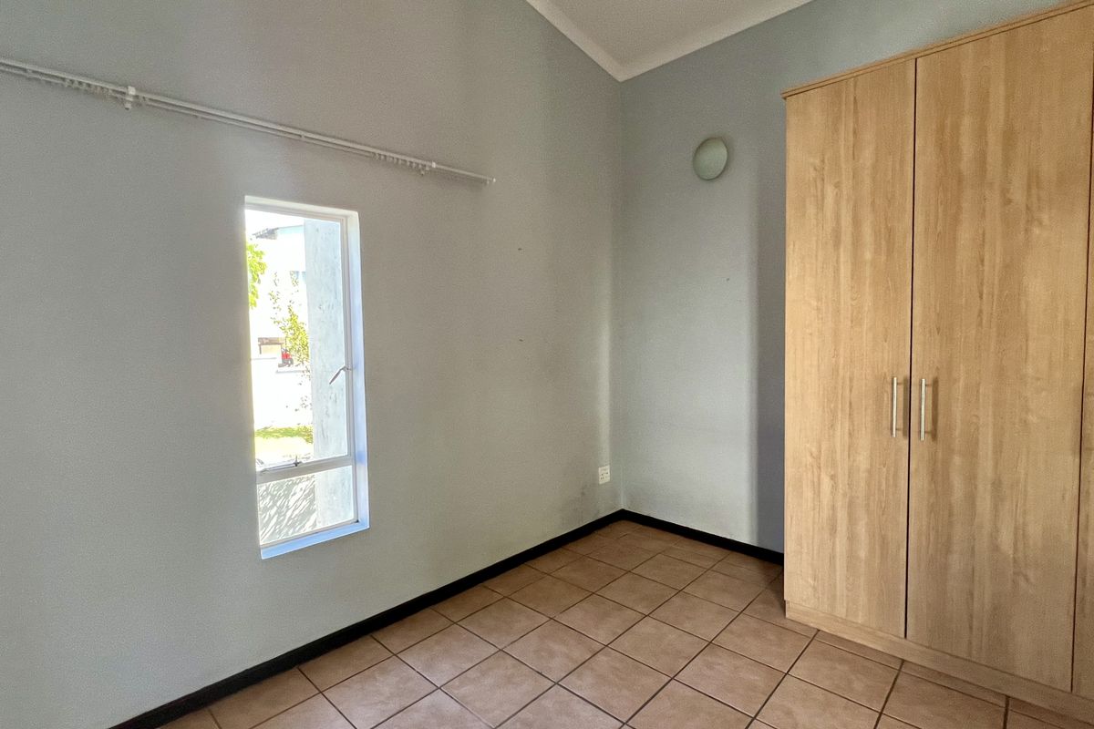 A bedroom featuring tiled flooring, a high ceiling, and a built-in wooden wardrobe.