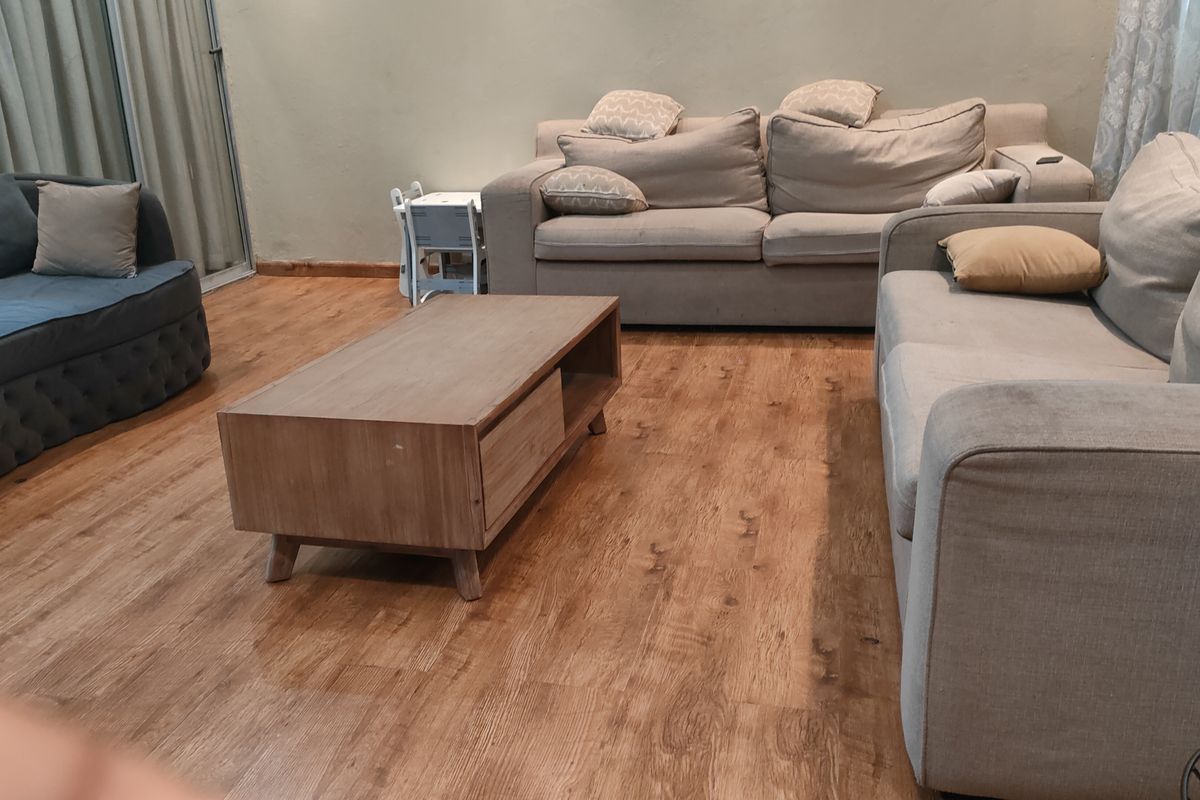 A spacious living room featuring wood-look laminate flooring and neutral wall tones, providing a comfortable and functional area for relaxation.