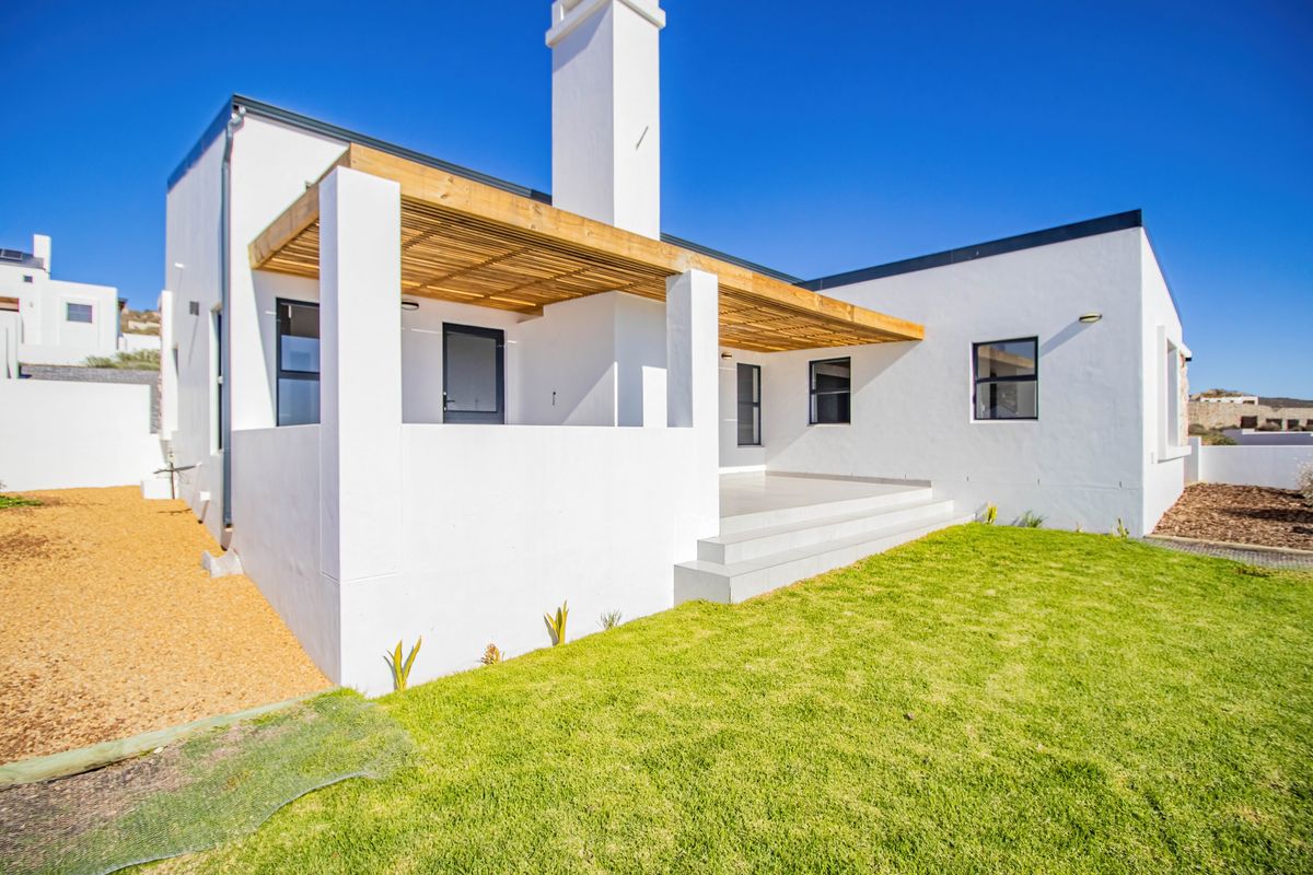 Rear view of a modern white house featuring a covered patio with timber pergola, concrete steps, and a well-maintained lawn.