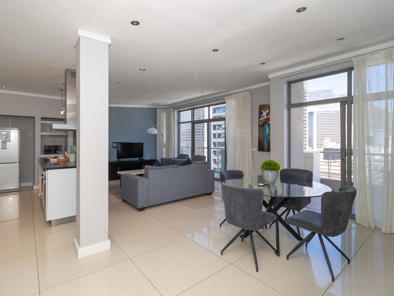 Spacious open-plan living and dining area featuring modern porcelain tiles, recessed lighting, and seamless access to a balcony with city views.