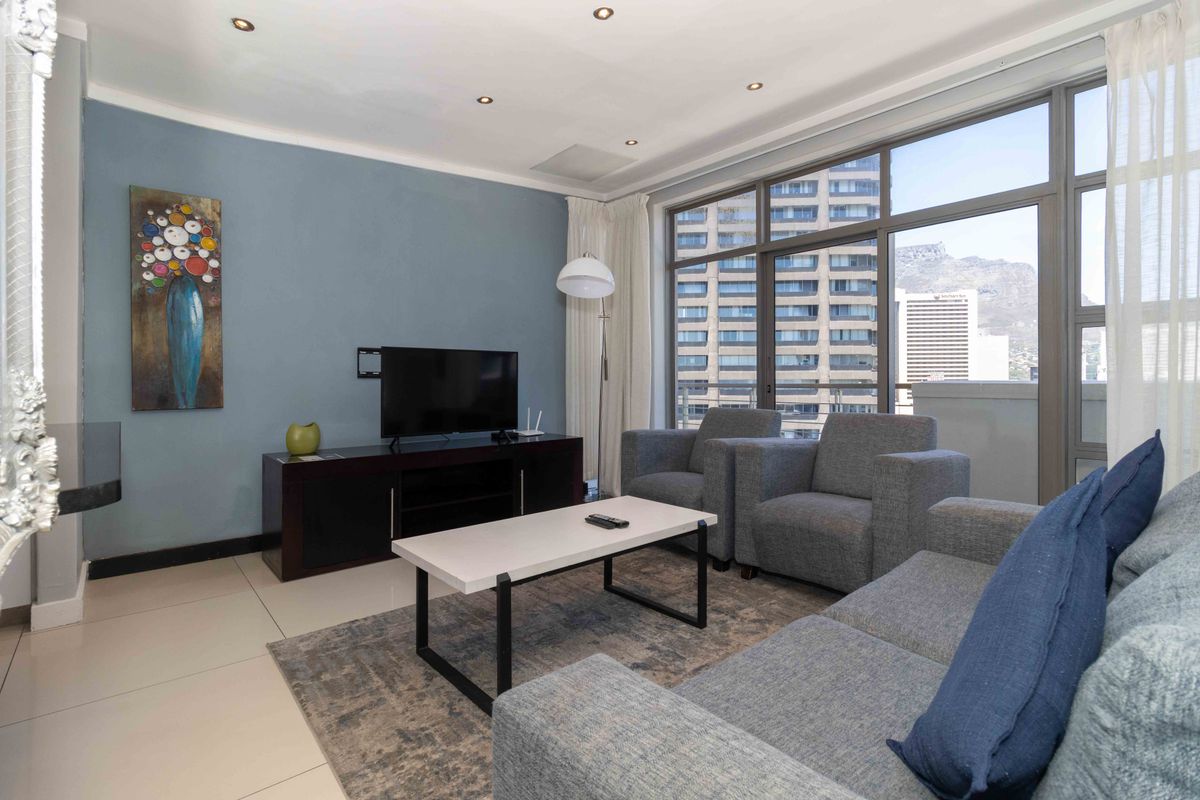 A bright living room featuring large floor-to-ceiling windows with city views, tiled flooring, and recessed downlighting.